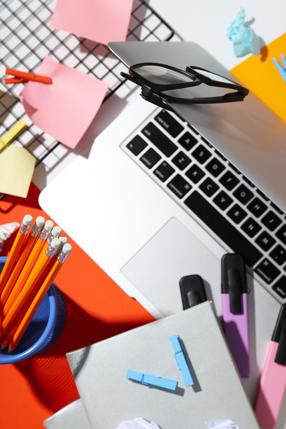 Computer, post-it, evidenziatori e occhiali su una scrivania