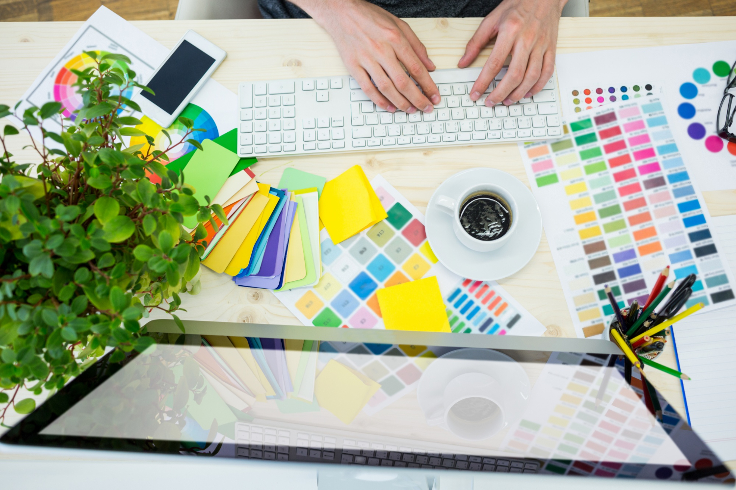 Scrivania con computer, tastiera palette di colori e tazza di caffè