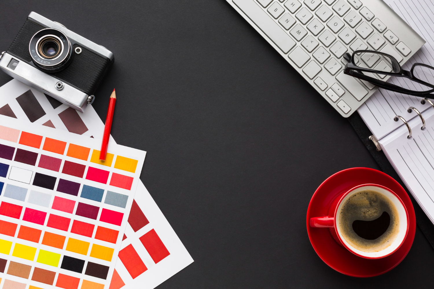 Scrivania con palette, macchina fotografica, tazza di caffè e tastiera computer