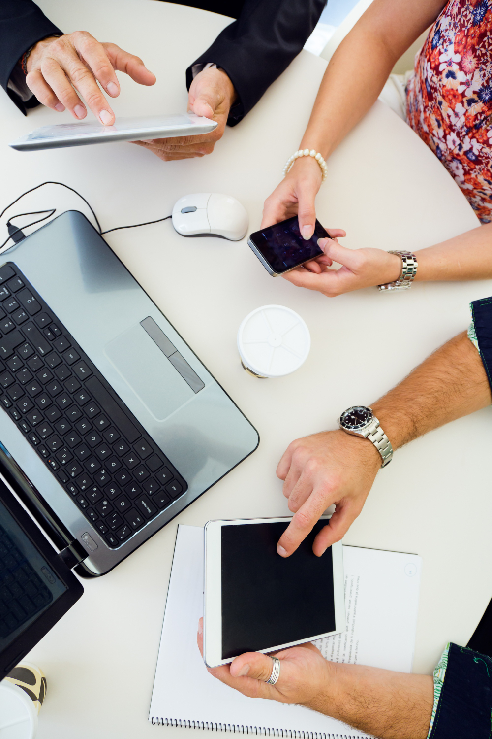 Una donna e due uomini alla scrivania con tablet, smartphone e laptop